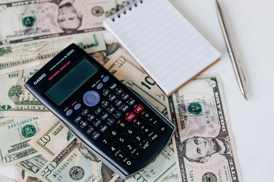 calculadora e um bloco de notas com notas de dóllares mostrando como investir no exterior