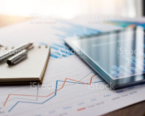 Business document report on paper and tablet with sales data and financial business growth graph on table background.