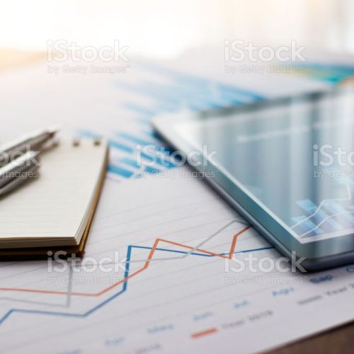 Business document report on paper and tablet with sales data and financial business growth graph on table background.